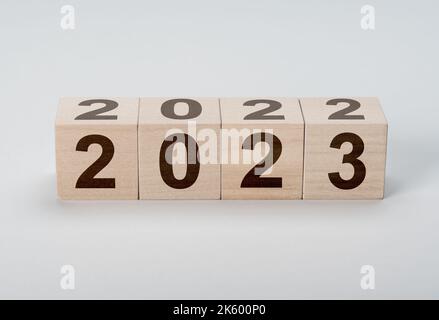 Blocchi di legno con 2022 2023 numero su sfondo grigio. Nuovo anno concetto. Cubo di legno con flip sopra blocco 2022 a 2023 parola. Gestione aziendale, Ins Foto Stock