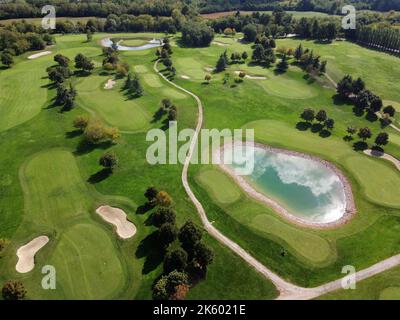 Paesaggio verde e aereo di un lussureggiante campo da golf con strade e laghetto tra alberi ben curati Foto Stock