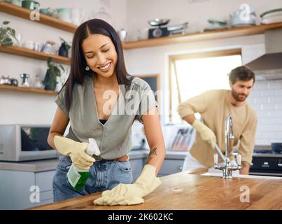 Felice giovane coppia interracial che pulisce la loro sede. Giovane uomo e donna che indossano i guanti mentre fanno le faccende insieme a casa. Pulizia femminile ispanica Foto Stock