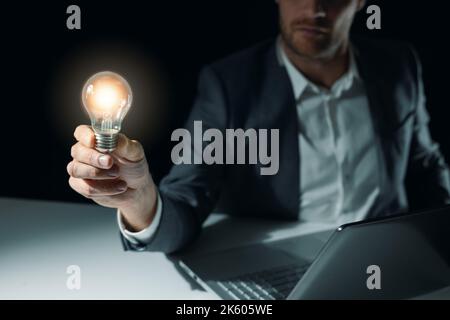 uomo d'affari che tiene a portata di mano una lampada luminosa. soluzioni aziendali, innovazione e concetto di nuova idea Foto Stock