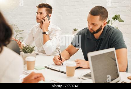 Uomo d'affari che parla durante una telefonata. Giovane architetto che scrive durante un incontro. Uomini d'affari in una riunione insieme. Ingegneri che lavorano insieme in un Foto Stock