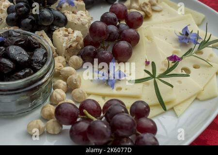 selezione di formaggi con uva e fiori commestibili Foto Stock
