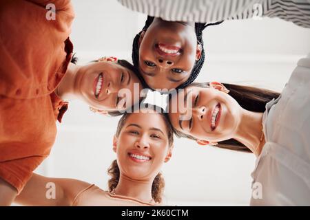 Ritratto di donne d'affari felici che uniscono le loro teste insieme in un cerchio in un ufficio sul lavoro. Gruppo vario di uomini d'affari allegri che si divertono Foto Stock