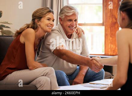 Immobiliare, casa di famiglia e coppia anziana fare la stretta di mano con l'agente per vendere casa. L'uomo anziano e la donna che si spostano per il pensionamento con i documenti Foto Stock