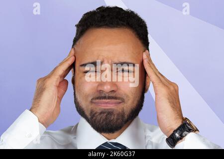 Giovane uomo d'affari afro-americano che soffre di mal di testa dopo una dura giornata lavorativa Foto Stock