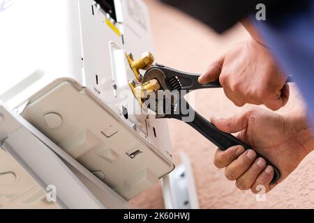 Strumenti e strumenti. Il riparatore maschio lavora con due chiavi regolabili contemporaneamente. Primo piano dei componenti di collegamento durante l'installazione del condizionatore d'aria. DIY c Foto Stock