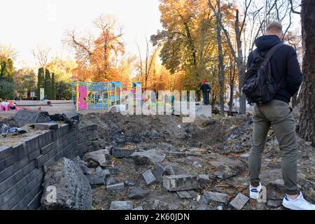 Kiev, Ucraina. 11th Ott 2022. Persone viste vicino all'imbuto dall'esplosione di un razzo russo su un parco giochi per bambini nel centro della capitale. Dopo diversi mesi di relativa calma, esplosioni multiple hanno oscillato Kyiv presto un lunedì mattina. Il capo dell’esercito ucraino ha detto che le forze russe hanno lanciato almeno 75 missili in Ucraina, con attacchi fatali alla capitale Kyiv, e alle città del sud e dell’ovest. Credit: SOPA Images Limited/Alamy Live News Foto Stock