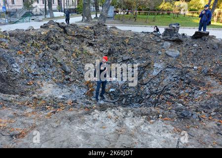 Kiev, Ucraina. 11th Ott 2022. Persone viste vicino all'imbuto dall'esplosione di un razzo russo su un parco giochi per bambini nel centro della capitale. Dopo diversi mesi di relativa calma, esplosioni multiple hanno oscillato Kyiv presto un lunedì mattina. Il capo dell’esercito ucraino ha detto che le forze russe hanno lanciato almeno 75 missili in Ucraina, con attacchi fatali alla capitale Kyiv, e alle città del sud e dell’ovest. Credit: SOPA Images Limited/Alamy Live News Foto Stock