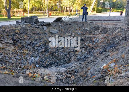 Kiev, Ucraina. 11th Ott 2022. Persone viste vicino all'imbuto dall'esplosione di un razzo russo su un parco giochi per bambini nel centro della capitale. Dopo diversi mesi di relativa calma, esplosioni multiple hanno oscillato Kyiv presto un lunedì mattina. Il capo dell’esercito ucraino ha detto che le forze russe hanno lanciato almeno 75 missili in Ucraina, con attacchi fatali alla capitale Kyiv, e alle città del sud e dell’ovest. Credit: SOPA Images Limited/Alamy Live News Foto Stock