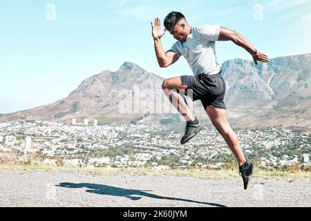 Giovane atletico uomo di razza mista che sprinting all'aperto nella natura. Adatta un bell'atleta maschile ispanico per una corsa. Fitness cardio e resistenza Foto Stock