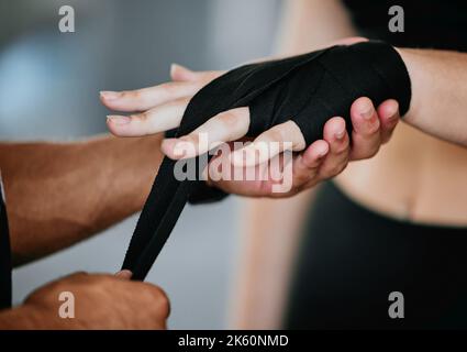 Primo piano di sconosciuto allenatore di corsa mista che avvolge mani di pugili caucasici in palestra. Allenatore ispanico ottenere kickboxer pronto con la mano avvolge per combattere in sé Foto Stock