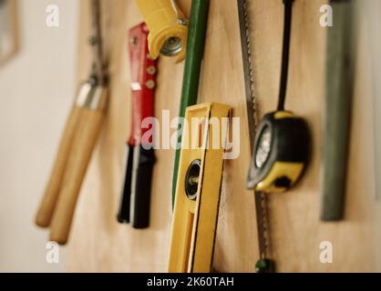 Una collezione di attrezzi e attrezzature assortiti su una parete. Attrezzi e attrezzature su una parete. Attrezzi di manutenzione appesi a una parete di legno. Ordinato, organizzato Foto Stock