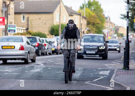 Un giovane uomo su una mountain bike che indossa una maschera scheletrica per mascherare il suo aspetto e senza casco lungo la strada principale di Wyke, Bradford, West Yorkshire, UKCredit: Windmill Images/Alamy Live News Foto Stock