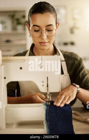 Misto design da corsa cucire un pezzo di denim. Giovane sarto usando una macchina da cucire. Creativa donna d'affari cucendo un pezzo di tessuto. Stilista di moda Foto Stock