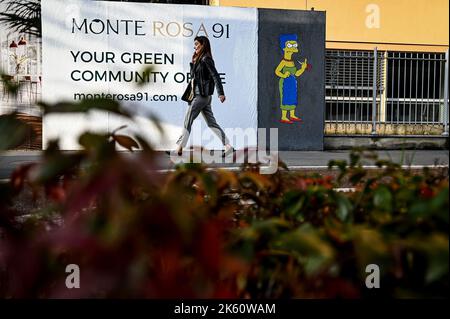 Milano, Italia il 11 ottobre 2022 una donna passa davanti a un murale intitolato ‘The Cut 2’ dell’artista di strada aleXsandro Palombo raffigurante il personaggio dei Simpson Marge Simpson tagliandosi i capelli e dando il dito medio in solidarietà con le donne iraniane di fronte al Consolato iraniano di Milano, Italia il 11 ottobre 2022. Una prima versione di un murale simile, intitolato 'The Cut' apparve il 5 ottobre nella stessa posizione ed è stata successivamente rimossa. Credit: Piero Crociatti/Alamy Live News Credit: Piero Crociatti/Alamy Live News Foto Stock