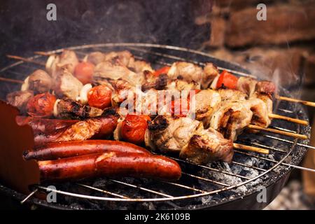 Spiedini di maiale alla griglia e salsicce, fuoco selettivo Foto Stock