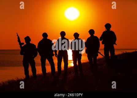 Soldati dell'esercito con fucili arancio silhouette tramonto Foto Stock