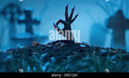 La mano di zombie fa il gesto giusto dalla tomba. Evento di festa Halloween concetto Foto Stock