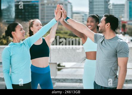 Gruppo vario di gente sportiva felice unendo le mani ai cinque alti per celebrare l'unità ed il sostegno. Gli atleti motivati si sono accoccolati per allenarsi Foto Stock