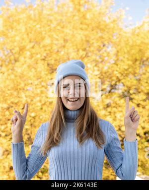 Donna autunnale positiva nel parco autunnale che dà un gesto di pollice in su. Clima caldo e soleggiato. Foto Stock