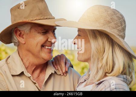 Primo piano di coppia sorridente anziana che abbraccia e si lega durante una giornata in una fattoria. Felice marito caucasico e moglie in piedi vicino insieme sul vigneto dentro Foto Stock