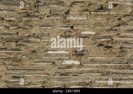 Vecchio muro di pietra tessitura, cemento, intonaco. Sfondo Foto Stock