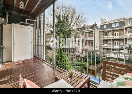 Sedie poste vicino al tavolo con piante in vaso e recinzione in metallo sul balcone che si affaccia edifici situati in città il giorno d'estate Foto Stock