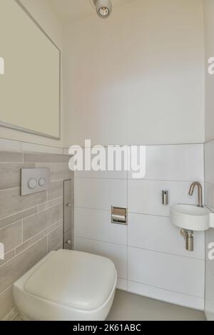 WC con ciotola in ceramica e piccolo lavabo nel bagno luminoso dell'appartamento moderno Foto Stock