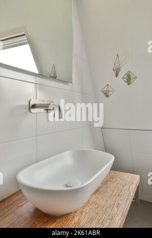 Lavabo in ceramica installato sul credenza vicino al telaio vuoto sotto lo specchio nel bagno moderno a casa Foto Stock