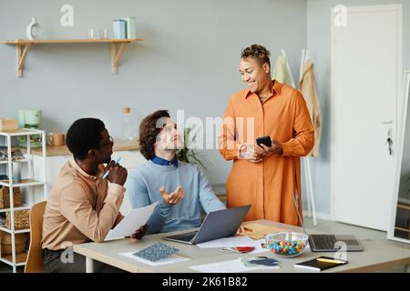 Ritratto di tre sorridenti uomini d'affari che discutono dello sviluppo del progetto durante una riunione e un lavoro in un ufficio di piccole aziende Foto Stock