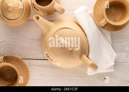 Due tazze di argilla su un piattino, una brocca di latte, una teiera e una ciotola di zucchero su un tavolo di legno, macro, vista dall'alto. Foto Stock