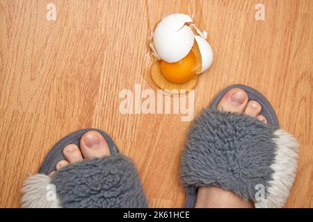 uovo rotto e piedi sul pavimento in cucina Foto Stock