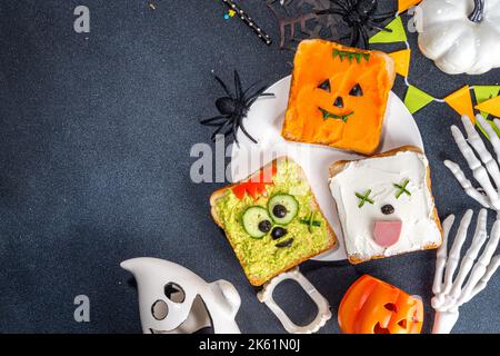 Cibo per bambini, feste o colazione Halloween idea. Semplice ricetta di panini sani da pane tostato, avocado, formaggio cremoso, zucca spalmata con Halloween Foto Stock