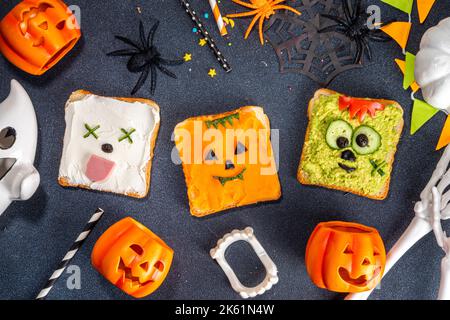 Cibo per bambini, feste o colazione Halloween idea. Semplice ricetta di panini sani da pane tostato, avocado, formaggio cremoso, zucca spalmata con Halloween Foto Stock