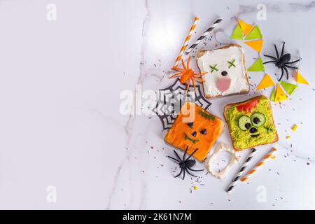 Cibo per bambini, feste o colazione Halloween idea. Semplice ricetta di panini sani da pane tostato, avocado, formaggio cremoso, zucca spalmata con Halloween Foto Stock