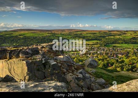 The Cow & Calf Rocks (vista panoramica rurale che domina il villaggio nella valle di Wharfe, alta brughiera, cielo blu) - Ilkley Moor, West Yorkshire, Inghilterra UK. Foto Stock