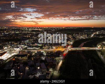 Strisce chiare dalle auto che si spostano attraverso un incrocio affollato dopo il tramonto Foto Stock