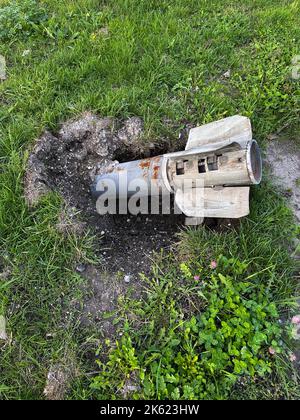 Proiettile russo MLRS Grad nel terreno vicino all'erba su liberato dal territorio di occupazione dell'Ucraina. Risultato del bombardamento russo. Concetto di Foto Stock