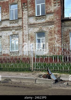 Proiettile russo MLRS Grad sulla strada accanto alla casa sulla libera dall'occupazione Kupiansk città in Ucraina. Risultato del bombardamento russo. Concetto Foto Stock