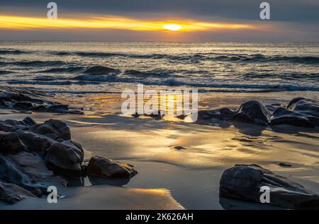 Nuvole pesanti da una tempesta lontano al mare bloccano l'alba. Ma una piccola pausa nelle nuvole lascia passare il Sole per renderlo una bella mattina. Foto Stock