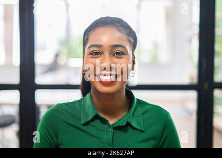 Ritratto di un'affascinante donna d'affari afro-americana che indossa una elegante camicia casual verde sorridendo alla macchina fotografica. Visualizzazione con webcam durante la videochiamata Foto Stock