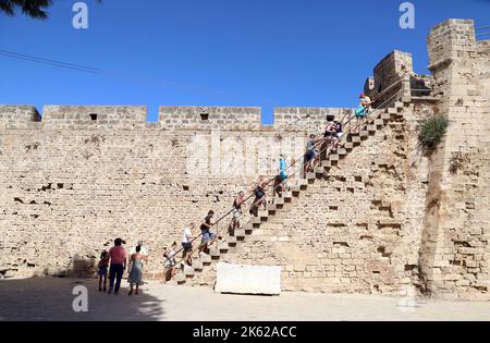 I turisti che si arrampicano sui gradini delle mura della città vecchia, Famagosta (Gazimagusa) Repubblica turca di Cipro del Nord Foto Stock