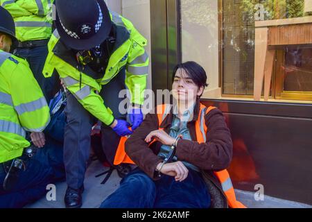 Londra, Regno Unito. 11th Ott 2022. Gli agenti di polizia arrestano un attivista Just Stop Oil che è stato incollato alla strada e bloccato Brompton Road a Knightsbridge durante la protesta. Il gruppo d'azione sul clima continua le sue proteste quotidiane chiedendo al governo britannico di non rilasciare nuove licenze per il petrolio e il gas. Credit: SOPA Images Limited/Alamy Live News Foto Stock