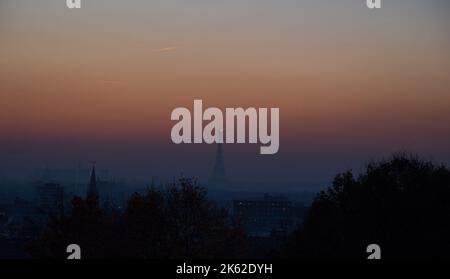 Vista del paesaggio urbano parigino con la torre Eiffel e le sagome delle chiese al tramonto dal parco di Belleville. Parigi, Francia. Foto Stock