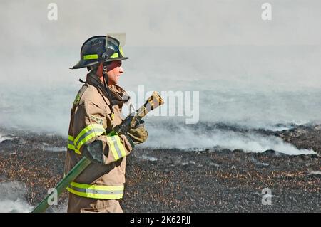 Vigili del fuoco che combattono un piccolo incendio a pennello nella zona di Atlanta con acqua e attrezzature di sicurezza Foto Stock