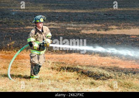 Vigili del fuoco che combattono un piccolo incendio a pennello nella zona di Atlanta con acqua e attrezzature di sicurezza Foto Stock