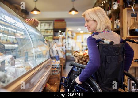 Donna in sedia a rotelle Shopping per cibo a Delicatessen Foto Stock