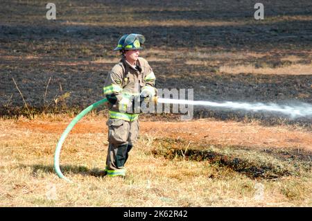 Vigili del fuoco che combattono un piccolo incendio a pennello nella zona di Atlanta con acqua e attrezzature di sicurezza Foto Stock