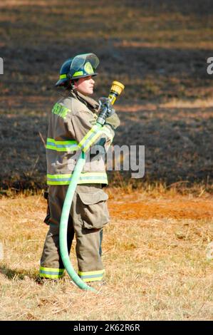 Vigili del fuoco che combattono un piccolo incendio a pennello nella zona di Atlanta con acqua e attrezzature di sicurezza Foto Stock