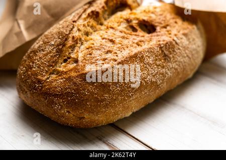 Pane fresco di grano saraceno su fondo di legno bianco. Una pagnotta di pane in un pacchetto. Foto Stock